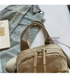 Detail of beige nylon bag showing the durable top handle and smooth double zipper closure