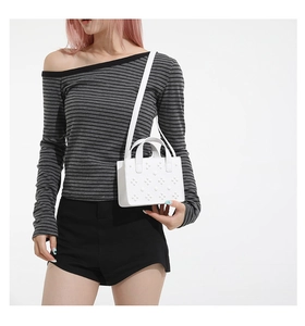 Détail d'un petit sac blanc carré à pois 3D avec bandoulière porté par un mannequin