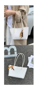 Detail of white woven tote bag featuring a colorful beaded tassel and soft PU leather texture