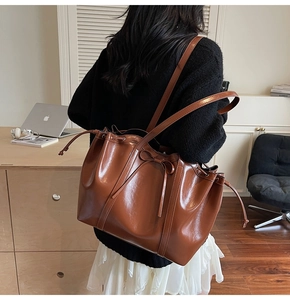 Detail of dark brown leather tote bag with drawstring closure and chic bow accent