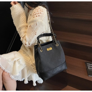 Detail of vintage black quilted tote with gold hardware and chain strap on a model