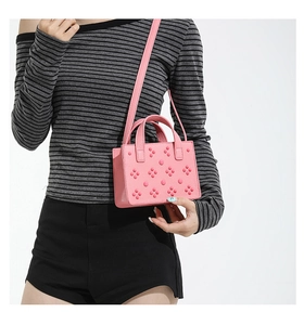 Gros plan du mini cabas rose en cuir avec clous floraux 3D et texture grainée