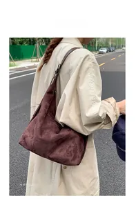 Detail view of large dark brown suede hobo bag showing soft texture and leather strap