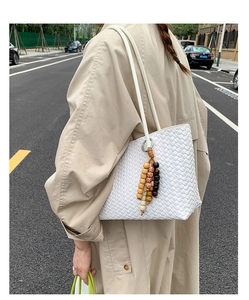 Detail of white woven leather tote bag with colorful wooden beads and fine texture