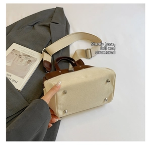 Detalle del bolso tote de lona con base de cuero, remaches metálicos y correa ancha