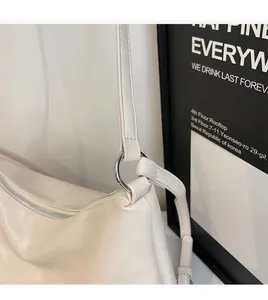 Detail of silver metal rings connecting strap to the cream faux leather tote bag