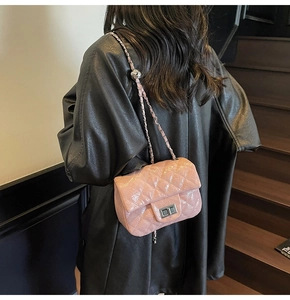 Détail du sac bandoulière rose matelassé avec chaîne argentée et boule en métal réglable