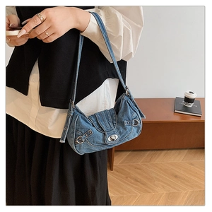 Detail of vintage denim underarm bag with metal buckles and Y2K rivets on blue canvas