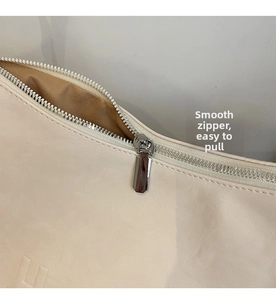 Detail of a smooth silver metal zipper on a beige large crossbody commuter bag