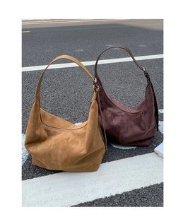 Detailed texture of suede hobo bags in tan and dark brown colors on street ground