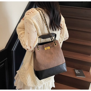 Detail of quilted leather bucket bag with gold chain strap and metal turn-lock closure