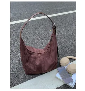 Detail of dark brown suede hobo bag texture and stitching on an asphalt background