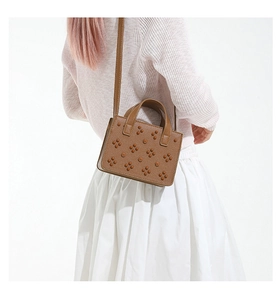 Sac à bandoulière en cuir marron à rivets porté par un mannequin, vue de dos