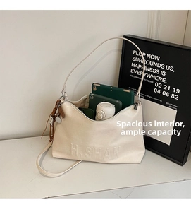 Detail of cream leather shoulder bag with embossed letters showing spacious interior capacity