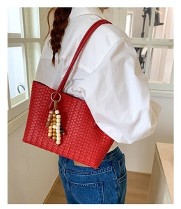 Detail of red hand-woven leather tote bag featuring stylish multi-color wooden bead tassels