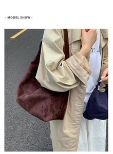Detail of large brown suede tote bag with wide leather strap on model in beige trench coat