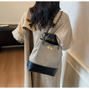 Detail of gray and black patchwork bucket bag with diamond stitching on a female model