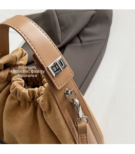 Détail du sac cabas en daim marron avec fermoir rotatif argenté et poignée en cuir lisse