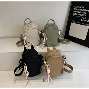 Detailed view of four colorful nylon crossbody bags with trendy beaded keychains