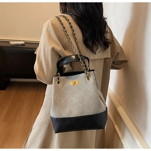 Detail of grey quilted bucket bag with chain strap styled with a trench coat