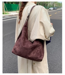 Detail of dark coffee suede hobo bag with adjustable buckle strap on casual outfit