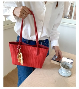 Detail of red woven tote bag with wooden bead tassel and elegant leather handles