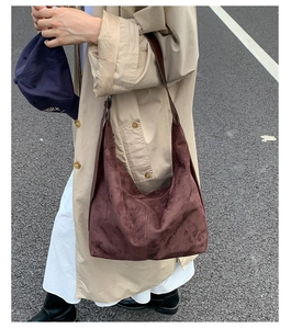 Detail of dark brown suede tote bag with vertical stitching and wide leather strap
