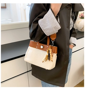 Detalle del bolso tote de lona y cuero con borla de cuentas de madera y remaches