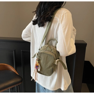 Detail of olive green nylon crossbody bag with 1865 tag and bead pendant charm