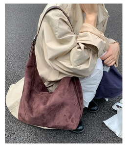 Detail of burgundy suede tote bag showing soft texture and slouchy hobo style on street