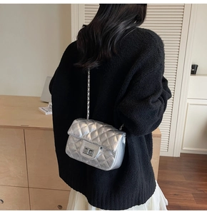 Détail du sac bandoulière argenté matelassé avec texture métallique et chaîne portée