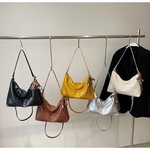 Detail view of five assorted PU leather tote bags hanging on display with H. SHAN logo