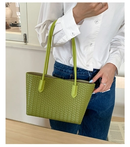 Detail of woven texture on a green shoulder tote bag shown with a casual outfit