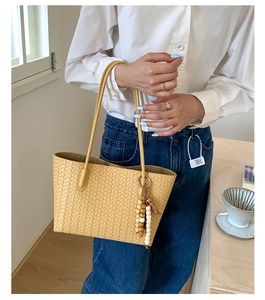 Detail of hand-woven tote bag showing intricate texture and decorative bead tassel charm