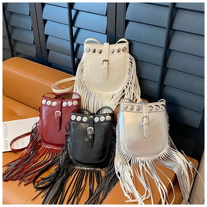 Bohemian tassel crossbody bags in white, red, black, and silver on a leather sofa
