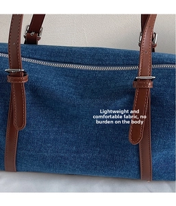 Dettaglio borsa tote in denim blu con tracolla in pelle marrone e fibbia metallica