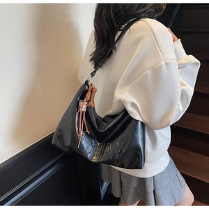 Detail of black leather tote bag with LSHAN embossed lettering and woven charm