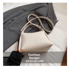 Détail du sac en cuir crème avec texture grainée et bandoulière réglable sur un blazer chic