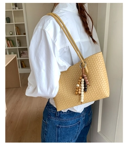 Detail of yellow woven tote bag with wooden bead charm and high-quality PU texture