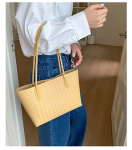 Close-up of yellow woven tote bag showing detailed texture and elegant shoulder straps