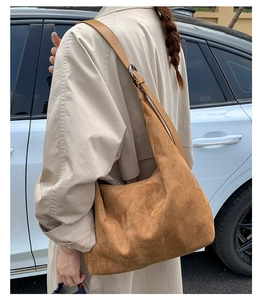 Outdoor shot of a brown suede hobo bag with adjustable leather strap and silver ring buckle