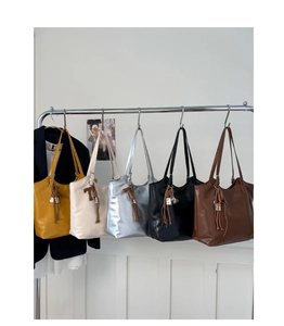 Detailed display of tote bags in yellow, white, silver, black, and brown with tassels