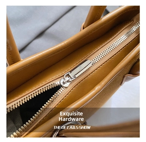 Detailaufnahme des silbernen Metallreißverschlusses und der braunen Lederstruktur am Tasche