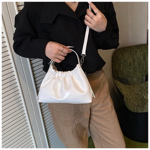 Bolso de mano blanco con diseño fruncido acabado brillante y correa ajustable sobre modelo