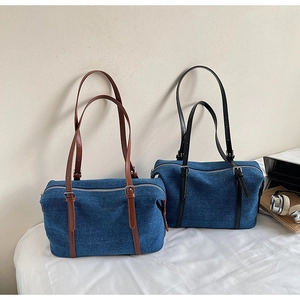 Dettaglio di grandi borse tote in denim con spalline regolabili e fibbie metalliche da viaggio