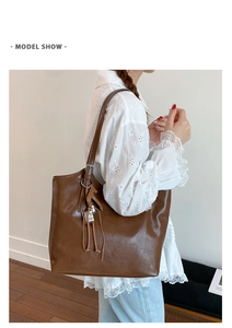 Detalle de bolso tote de cuero sintético marrón con colgante de caballo y correa ajustable