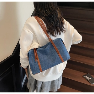 Vista dettagliata della grande borsa tote in denim con cinturini in pelle su una modella