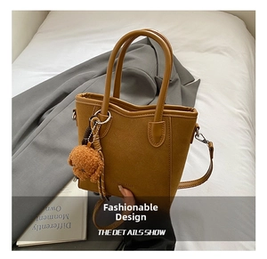 Details zur braunen Eimer-Tasche aus Mattleder mit Riemen und Teddybär-Anhänger