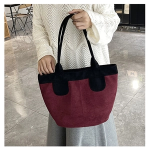 Détail du sac cabas bordeaux et noir en cuir mat porté par un mannequin