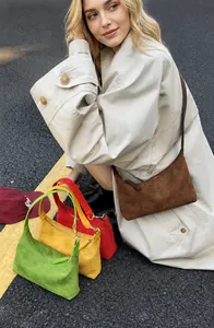Detail of minimalist suede hobo bags in brown, red, yellow and green colors